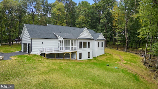 back of house featuring a deck, a garage, and a lawn