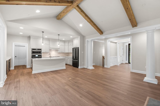 kitchen featuring hanging light fixtures, white cabinetry, a kitchen island with sink, vaulted ceiling with beams, and stainless steel appliances