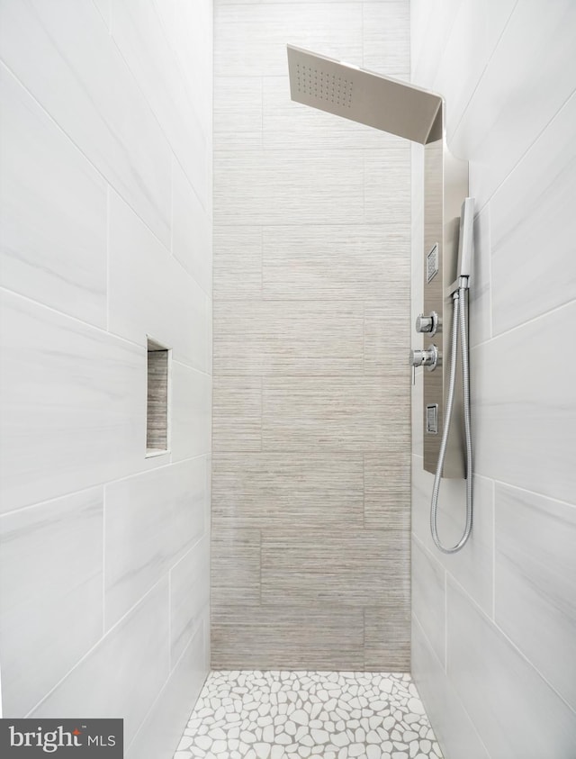 bathroom featuring a tile shower, tile patterned floors, and tile walls