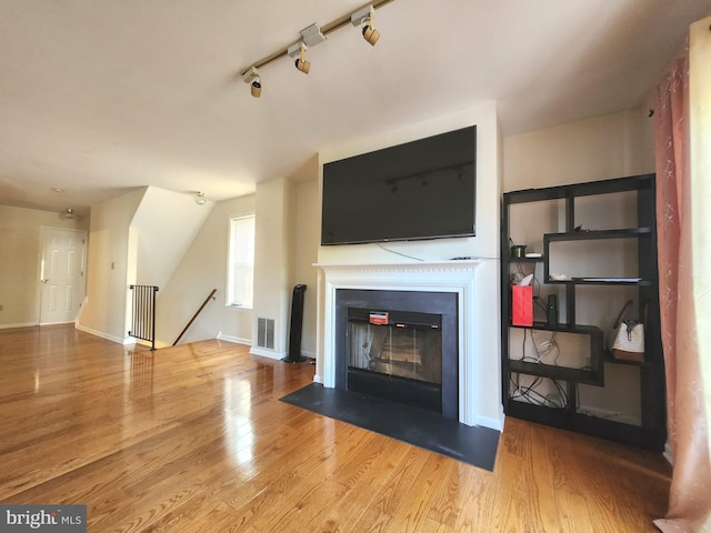 unfurnished living room with wood-type flooring and rail lighting