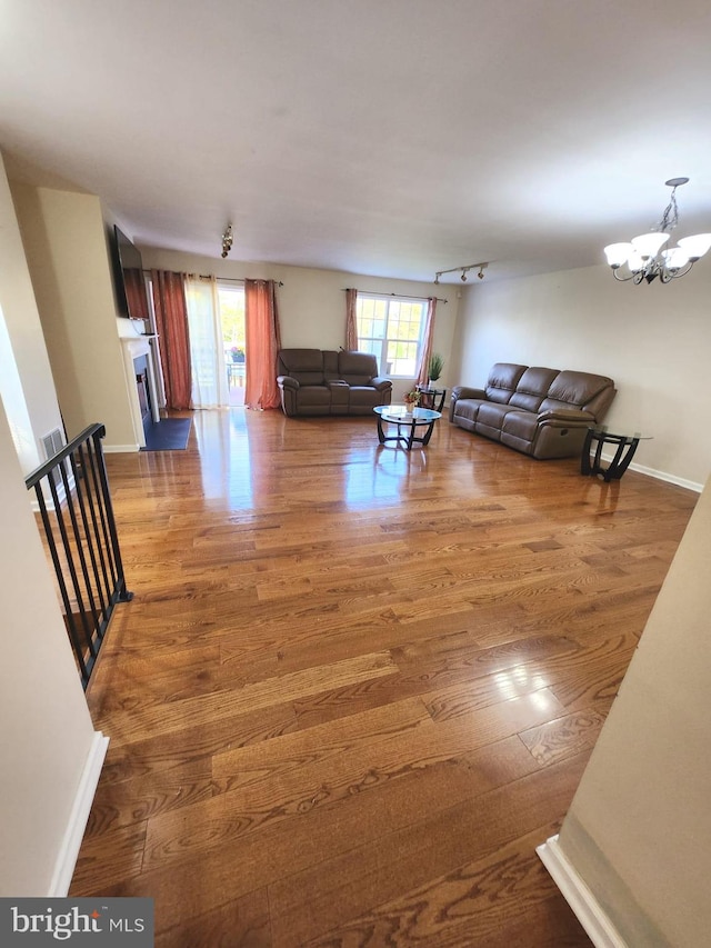 unfurnished living room with an inviting chandelier and dark hardwood / wood-style flooring