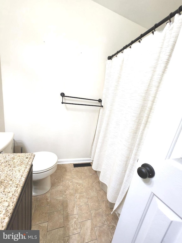 bathroom with walk in shower, vanity, and toilet