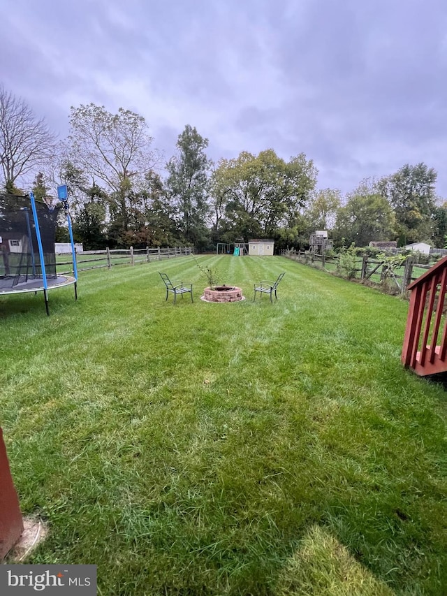 view of yard featuring a trampoline and an outdoor fire pit