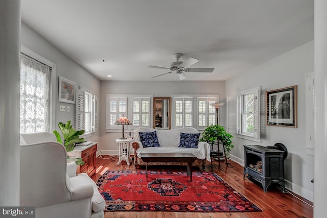 living room with hardwood / wood-style floors, ceiling fan, a healthy amount of sunlight, and a wood stove