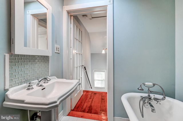 bathroom featuring sink, a tub, and tasteful backsplash