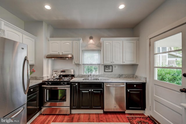 kitchen featuring sink, stainless steel appliances, light stone counters, white cabinets, and light wood-type flooring