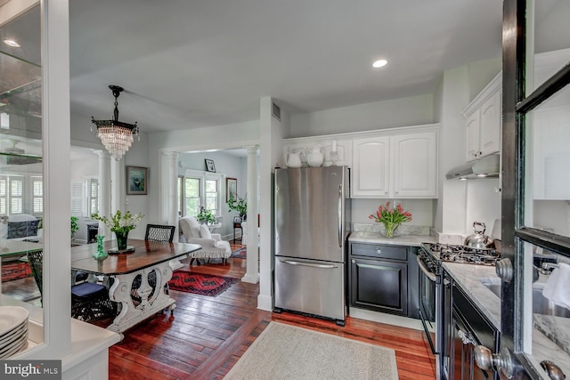 kitchen featuring light wood-type flooring, appliances with stainless steel finishes, a notable chandelier, white cabinetry, and decorative columns