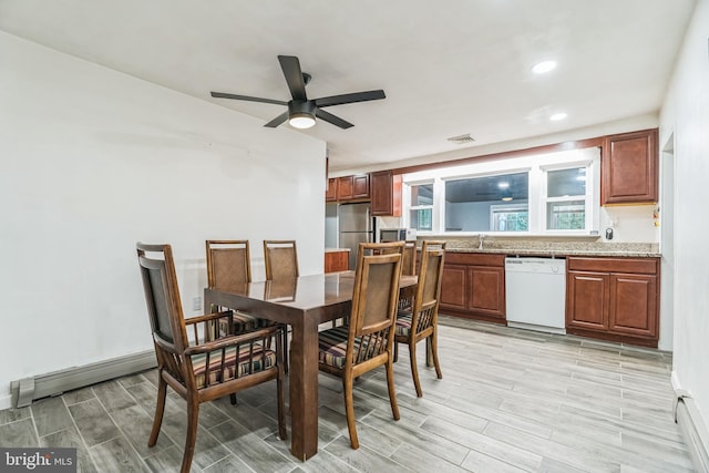 dining space with ceiling fan, a baseboard heating unit, and sink