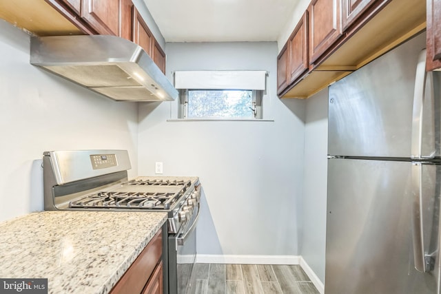 kitchen with light stone countertops, stainless steel appliances, and extractor fan