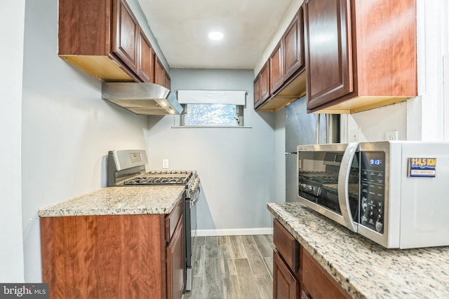 kitchen featuring gas stove, light stone counters, and range hood