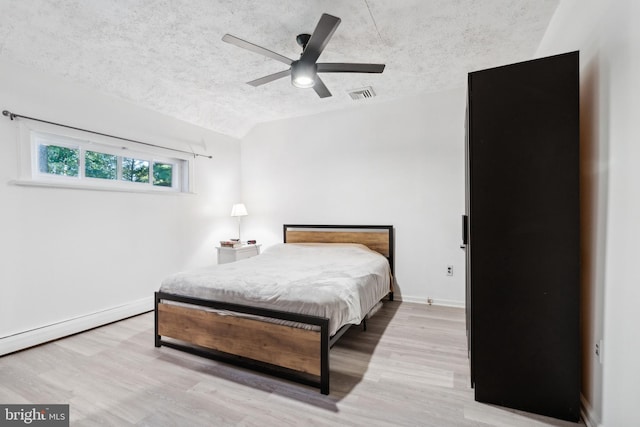 bedroom with vaulted ceiling, ceiling fan, baseboard heating, a textured ceiling, and light hardwood / wood-style floors