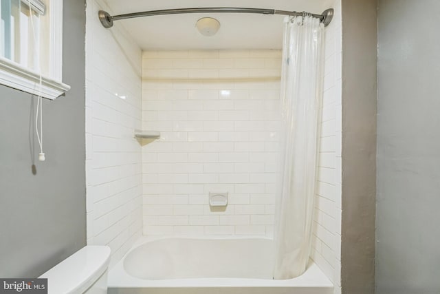 bathroom featuring shower / tub combo and toilet