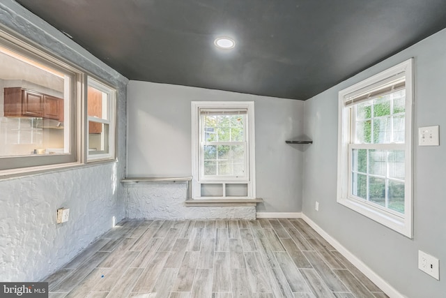 spare room featuring light hardwood / wood-style floors, a wealth of natural light, and lofted ceiling