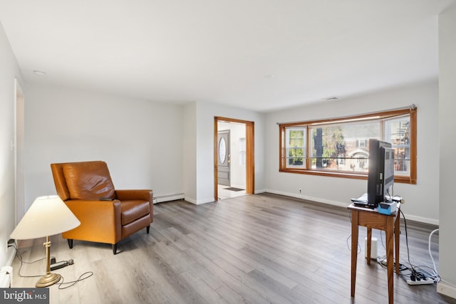 living area with hardwood / wood-style floors and a baseboard heating unit