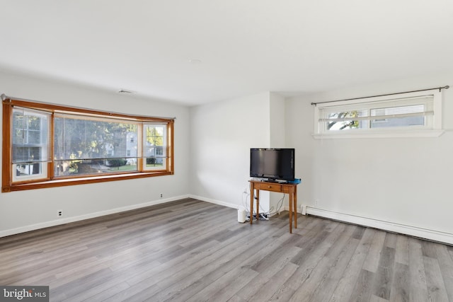 unfurnished living room featuring light wood-type flooring and a baseboard radiator