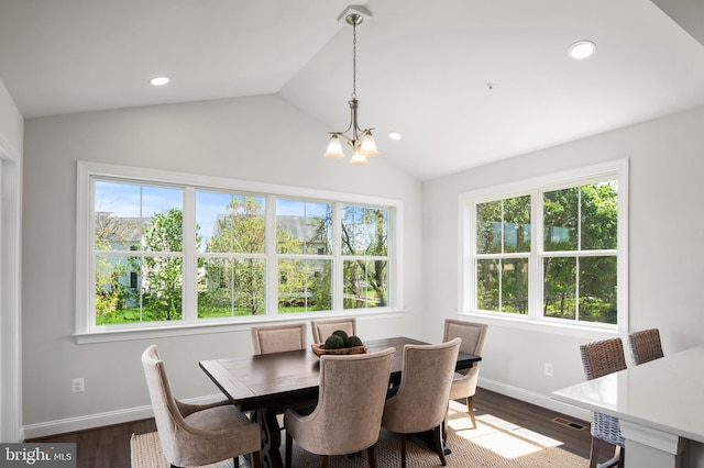 dining area featuring lofted ceiling, a wealth of natural light, dark hardwood / wood-style floors, and an inviting chandelier