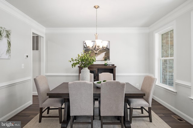 dining space featuring a chandelier, dark hardwood / wood-style floors, and crown molding