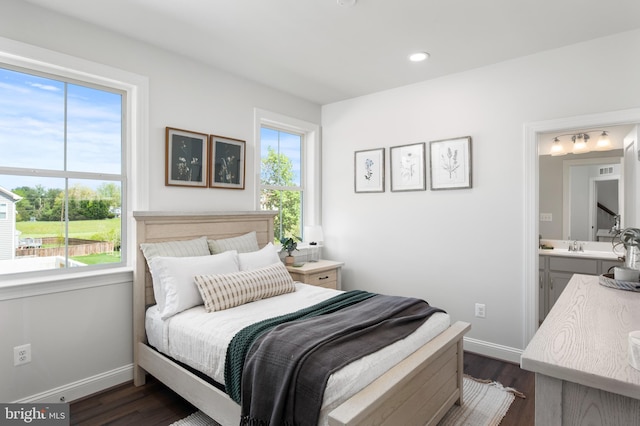 bedroom with ensuite bath, dark wood-type flooring, and multiple windows