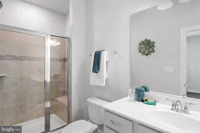 bathroom featuring vanity, a shower with shower door, and toilet