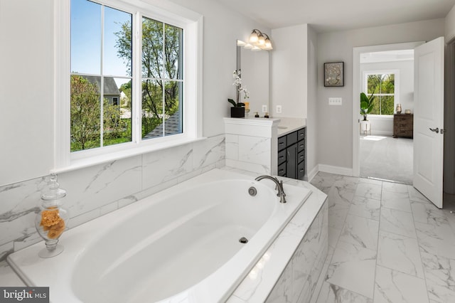 bathroom with tiled tub and vanity