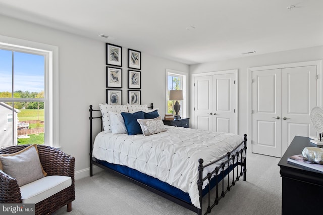 bedroom with two closets and light colored carpet