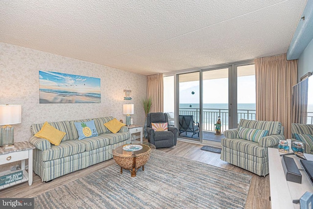 living room featuring hardwood / wood-style flooring, a wall of windows, a textured ceiling, and a water view