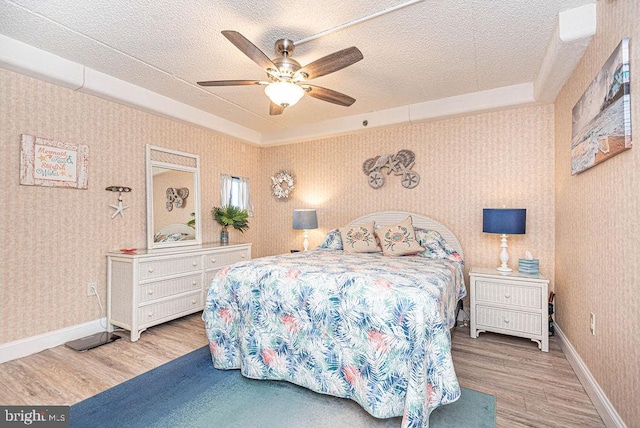 bedroom with hardwood / wood-style flooring, ceiling fan, and a textured ceiling