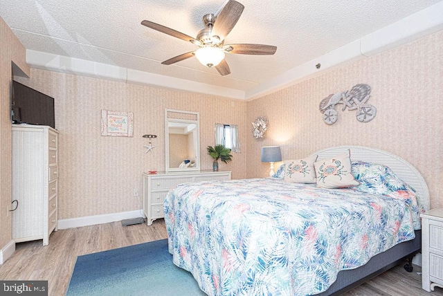 bedroom with ceiling fan, light hardwood / wood-style floors, and a textured ceiling