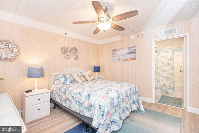 bedroom featuring a textured ceiling, connected bathroom, light wood-type flooring, and ceiling fan