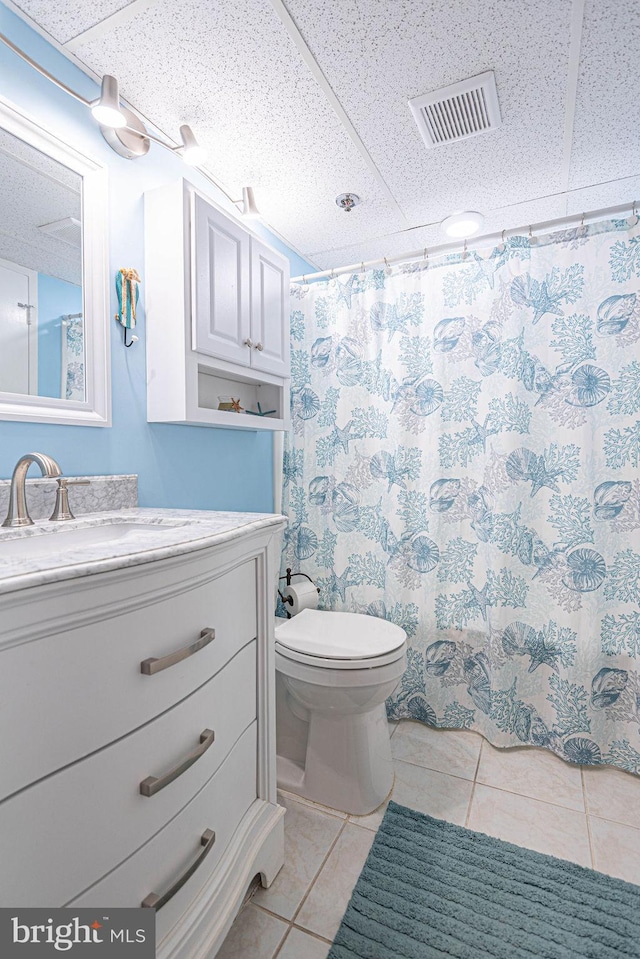 bathroom featuring tile patterned floors, toilet, vanity, and curtained shower