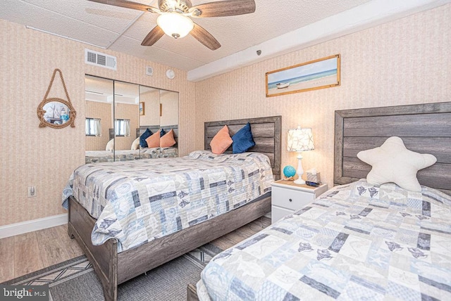 bedroom featuring a closet, hardwood / wood-style floors, a textured ceiling, and ceiling fan