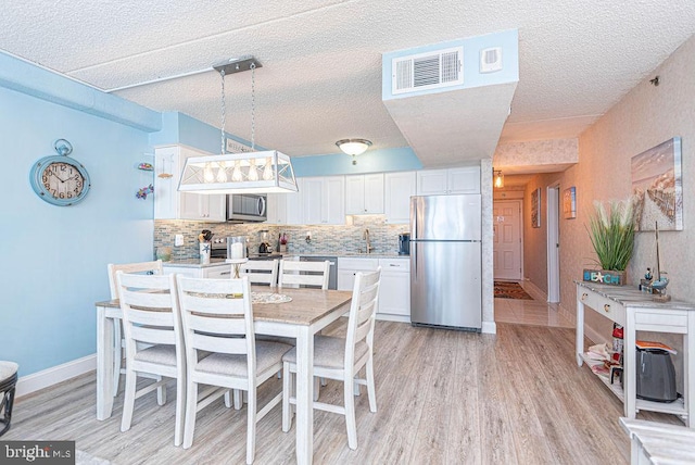 dining room with a textured ceiling, light wood-type flooring, and sink