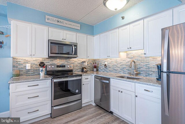 kitchen featuring light hardwood / wood-style flooring, stainless steel appliances, sink, and white cabinetry