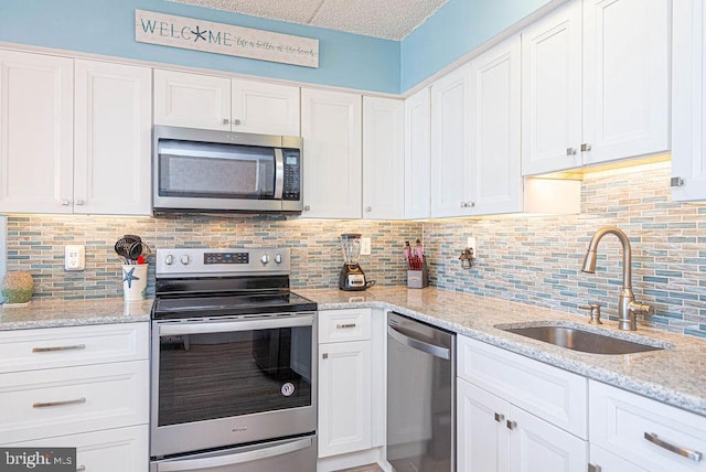 kitchen featuring backsplash, white cabinets, appliances with stainless steel finishes, and sink