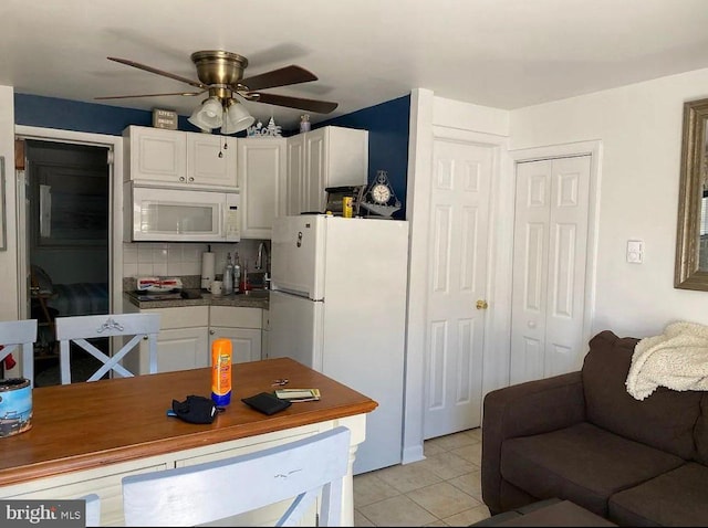 kitchen with white cabinets, light tile patterned flooring, white appliances, and tasteful backsplash