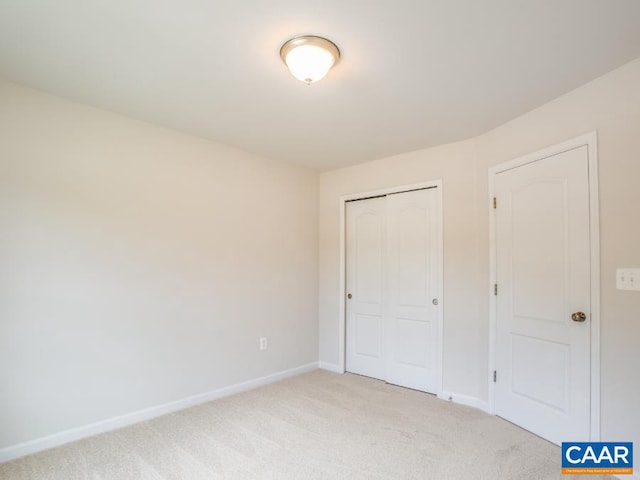 unfurnished bedroom featuring light carpet and a closet