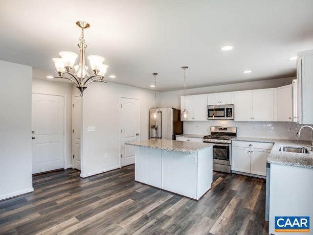 kitchen featuring appliances with stainless steel finishes, a kitchen island, decorative light fixtures, and sink