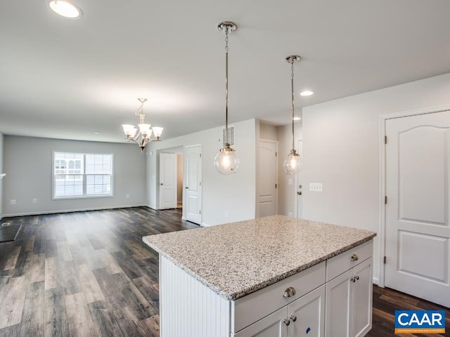 kitchen with light stone counters, decorative light fixtures, white cabinetry, a center island, and dark hardwood / wood-style flooring