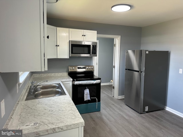 kitchen featuring light hardwood / wood-style floors, appliances with stainless steel finishes, sink, and white cabinets