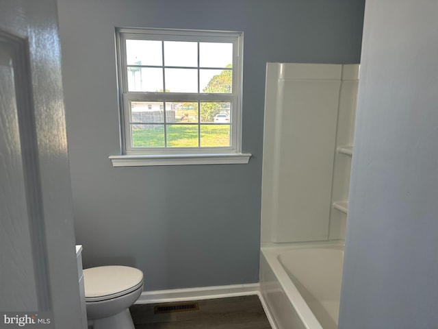 bathroom featuring hardwood / wood-style flooring, toilet, and a washtub