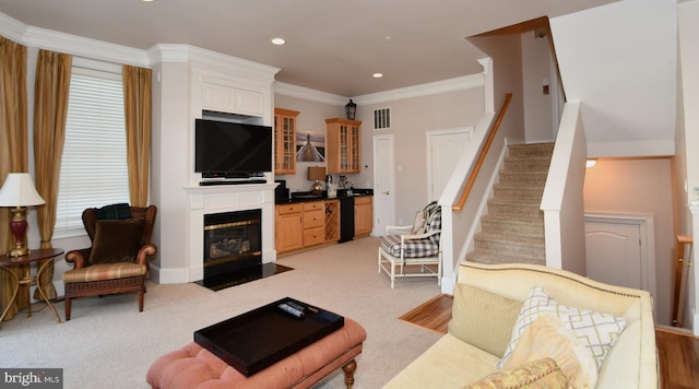 living area featuring visible vents, ornamental molding, stairway, a large fireplace, and light colored carpet