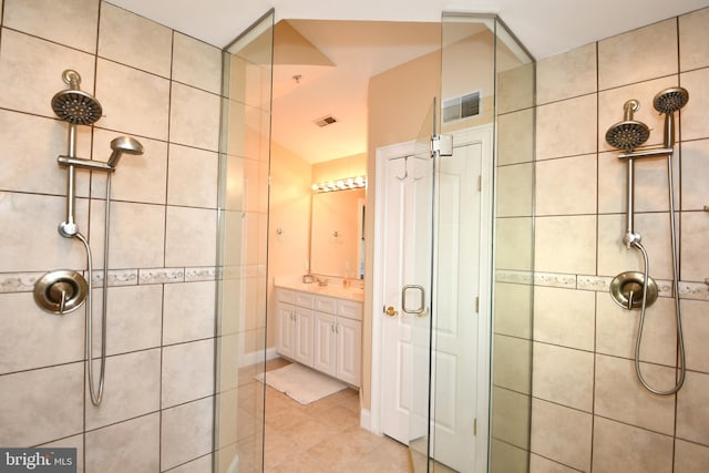 bathroom with visible vents, tiled shower, vanity, and tile patterned flooring