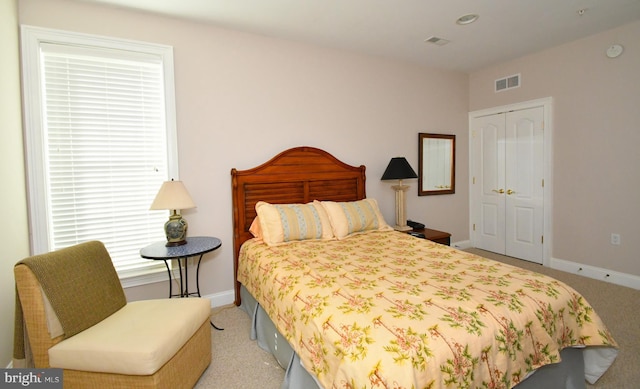 bedroom with a closet, baseboards, carpet floors, and visible vents