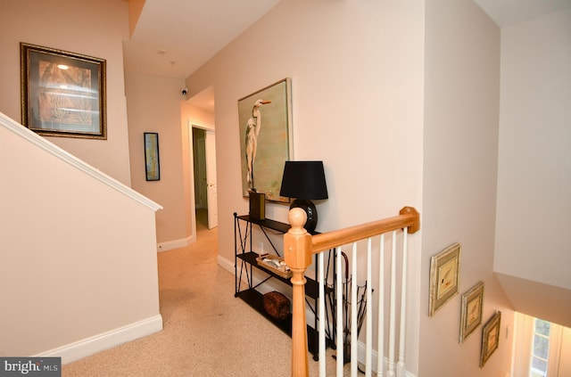 hallway with baseboards, an upstairs landing, and carpet flooring