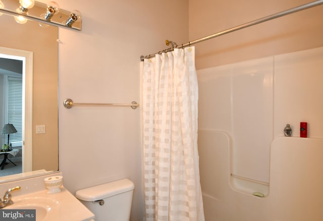 full bath with curtained shower, toilet, and a sink