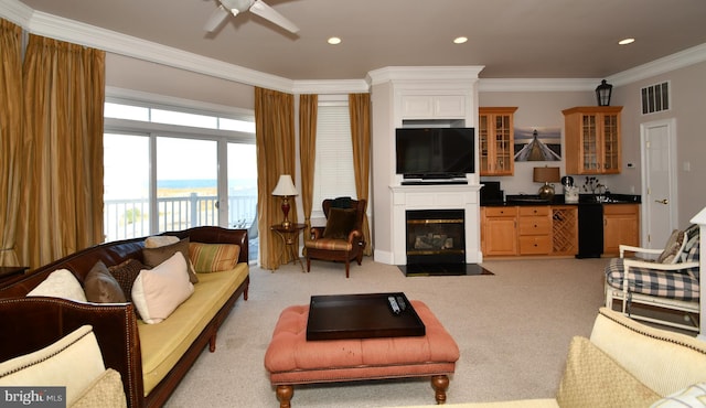 living area with visible vents, a fireplace with flush hearth, ornamental molding, a ceiling fan, and wet bar