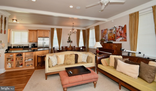 living area with ceiling fan with notable chandelier, recessed lighting, wood finished floors, and ornamental molding