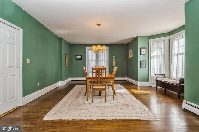 dining room featuring an inviting chandelier, baseboard heating, and dark hardwood / wood-style flooring