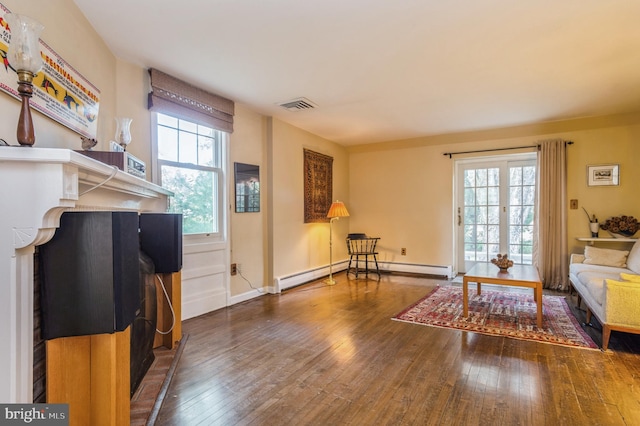 living room featuring a healthy amount of sunlight, baseboard heating, and hardwood / wood-style floors