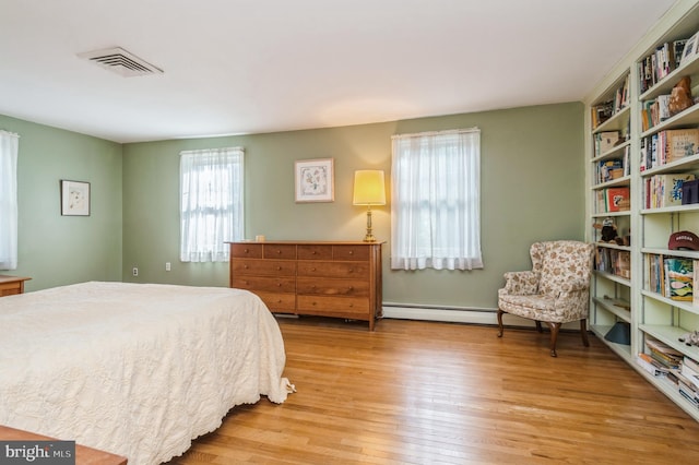 bedroom with a baseboard radiator and light wood-type flooring